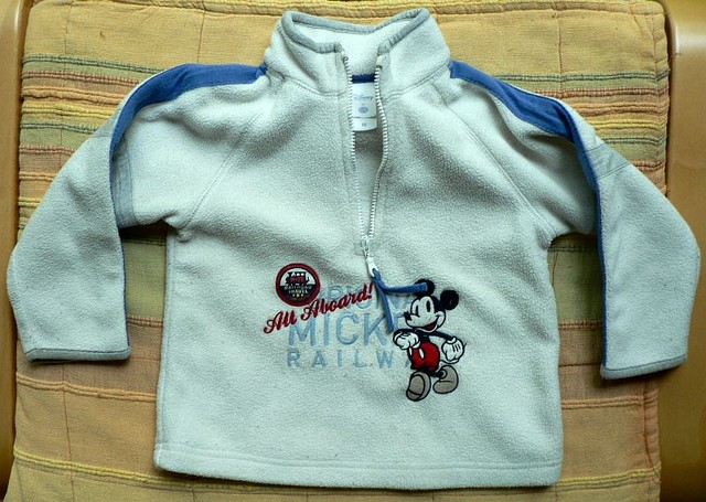 Písková mikina s modrými lampasy a výšivkou Mickey mouse na hrudi. Polyester,  zn. Disney, vel. 86. Nošená, žmolíky, 40 Kč.
